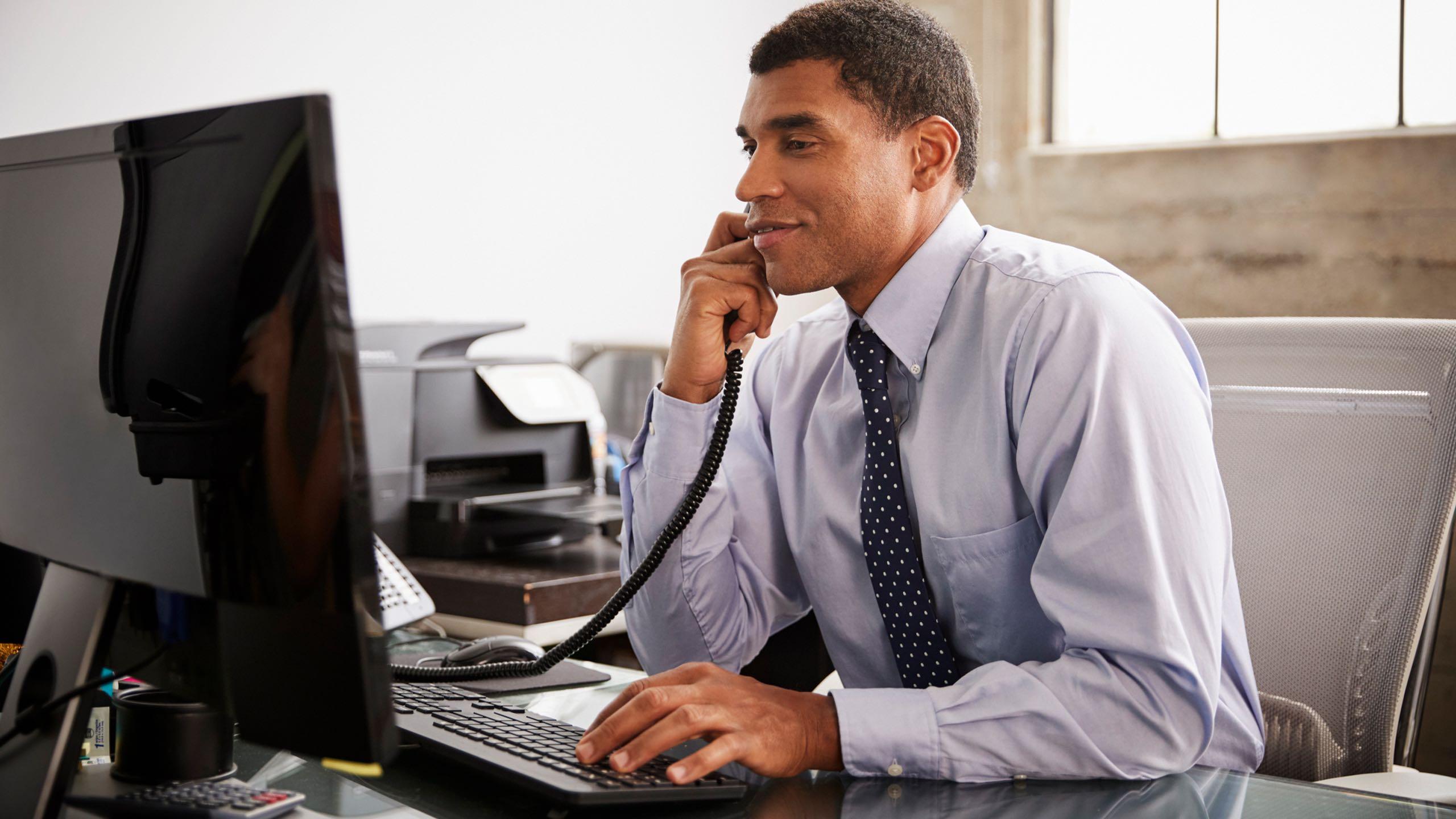 Gentleman on phone in front of computer