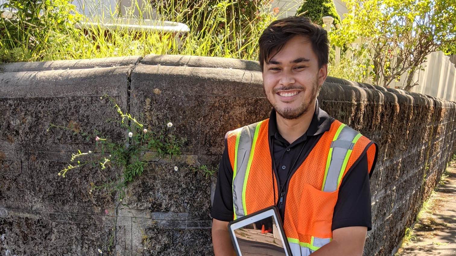 Sonic employee in orange safety vest holding tablet